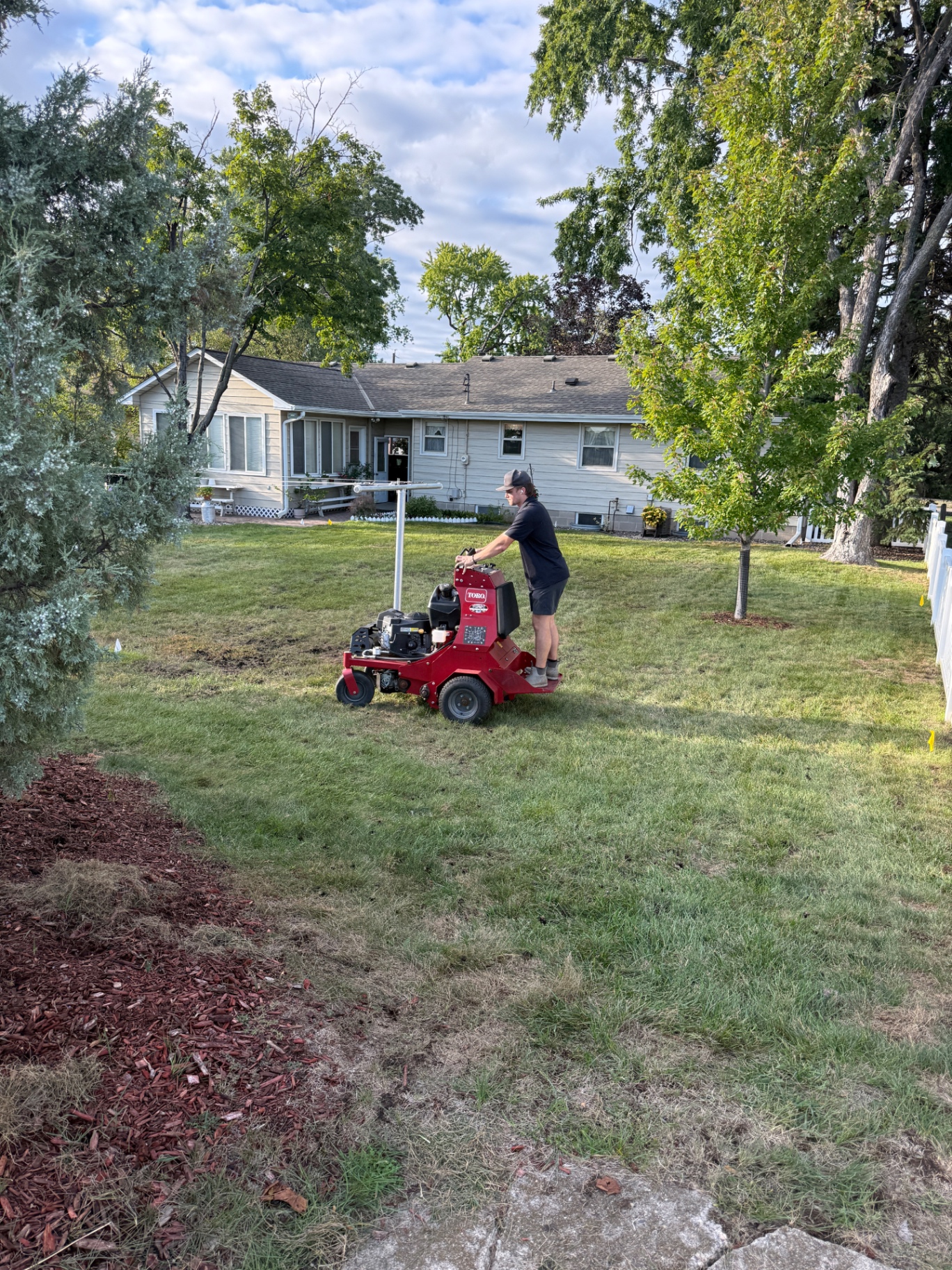 Core aerating a Minnesota backyard lawn with sprinkler heads flagged